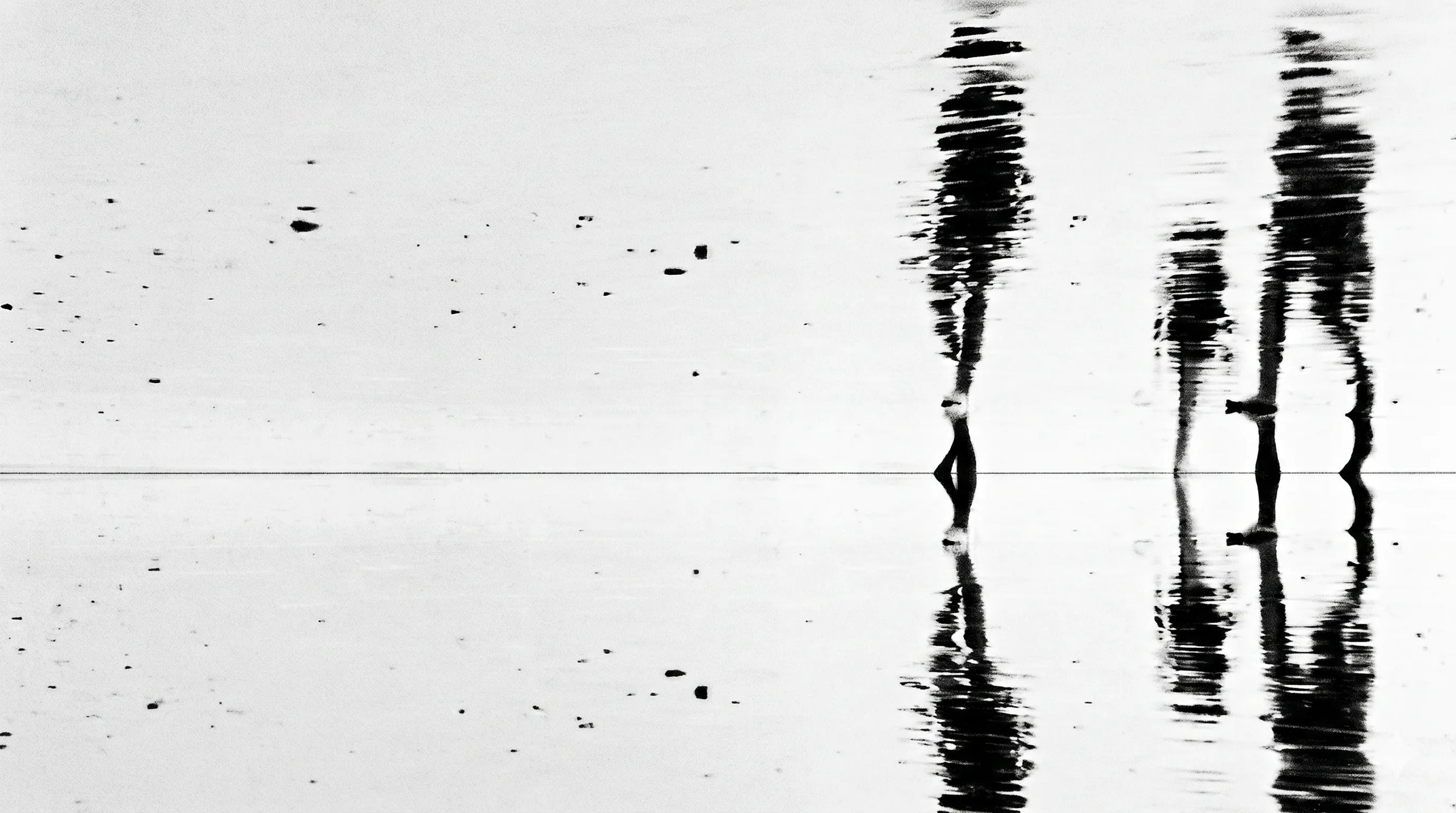 Zwei verschwommene menschliche Silhouetten in Bewegung auf einer reflektierenden Oberfläche, körniges Schwarz-Weiß-Bild — das visuelle Manifest von Wellness Anarchy